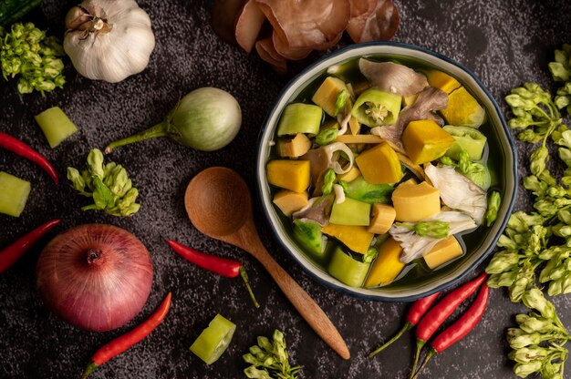 Kaeng Liang in a bowl with spices on a black cement floor.