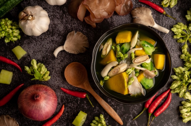 Kaeng Liang in a bowl with spices on a black cement floor.