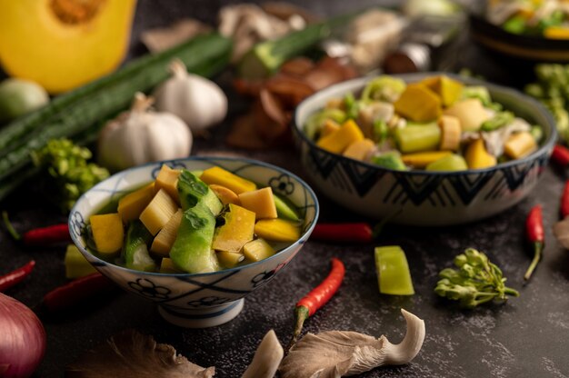 Kaeng Liang in a bowl with spices on a black cement floor.