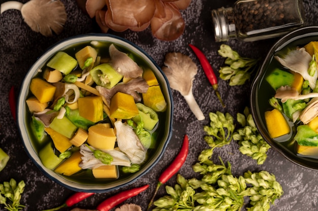 Kaeng Liang in a bowl with spices on a black cement floor.