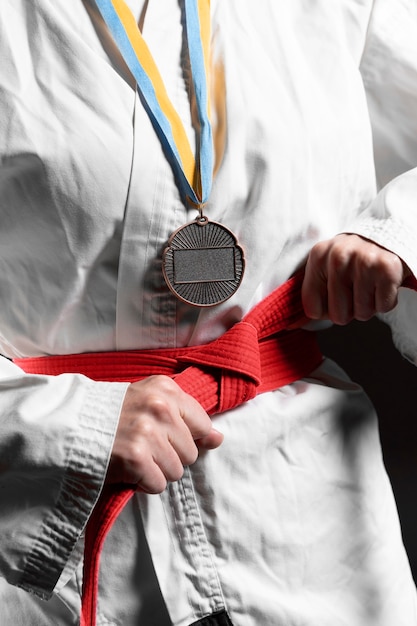 Karate athlete with red belt and medal closeup