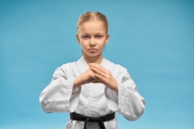 Ragazza di karate con cintura nera praticando la posizione delle mani.