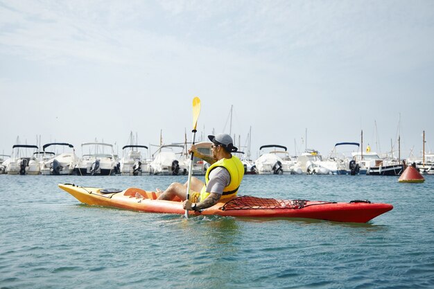 Kayaking man in cap and yellow safety jacket