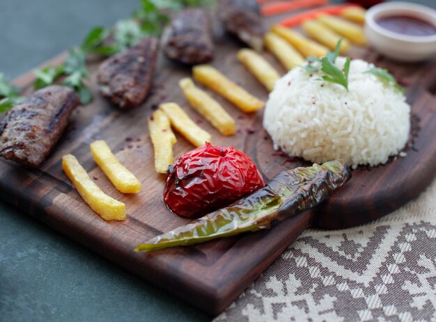 Kebab board with french fires, grilled foods and rice. 