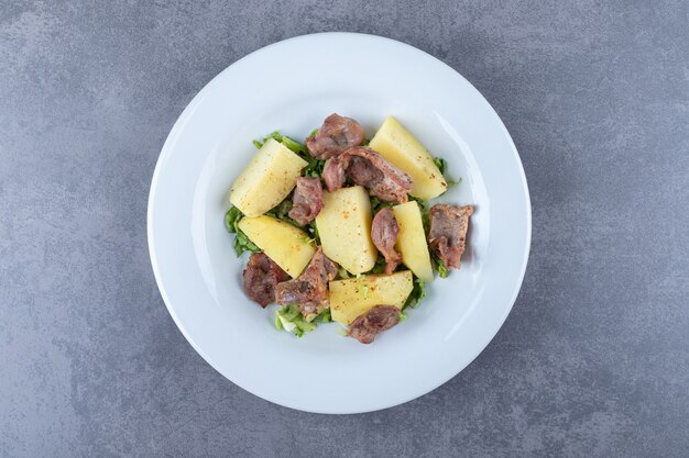 Kebab pieces and boiled potatoes on white plate.