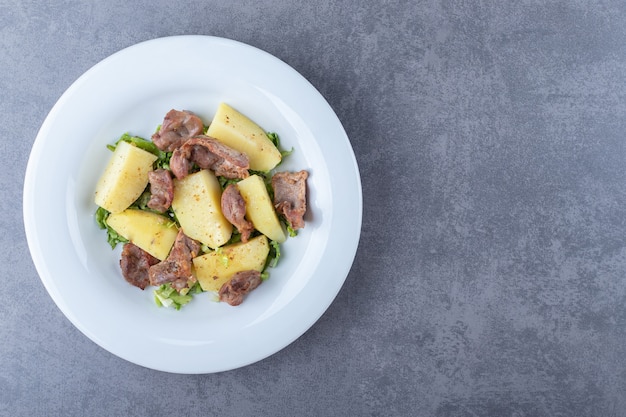 Kebab pieces and boiled potatoes on white plate.