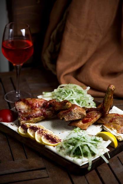 Kebab servito con cipolla tritata, pezzo di limone e vino rosso