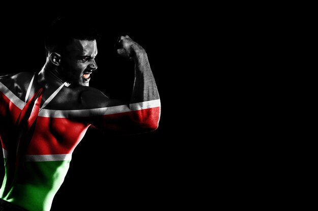 잘생긴 젊은 근육 질의 남자 검은 배경에 케냐 국기