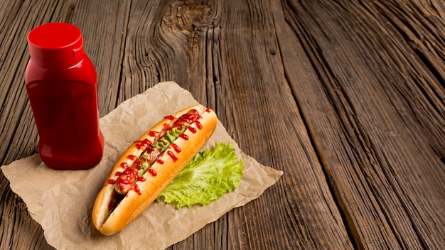 Ketchup and hot dog on wooden background