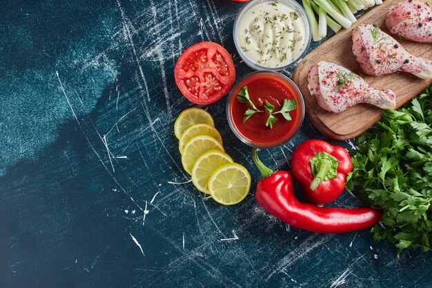 Ketchup and mayonnaise sauces with herbs and raw chicken legs.