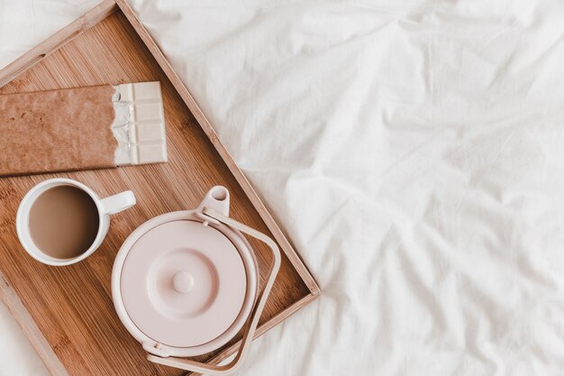 Kettle, chocolate and hot drink on white bedsheet