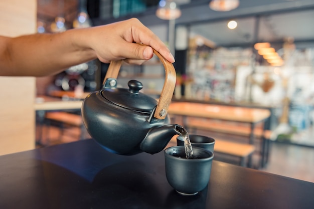 커피 숍에서 커피 타임 동안 컵에 끓는 물을 붓는 주전자