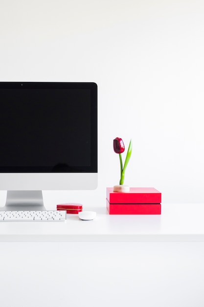 Keyboard near monitor, computer mouse and decorative flower on table