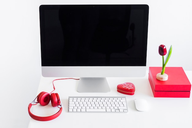 Keyboard near monitor, computer mouse and headphones on table