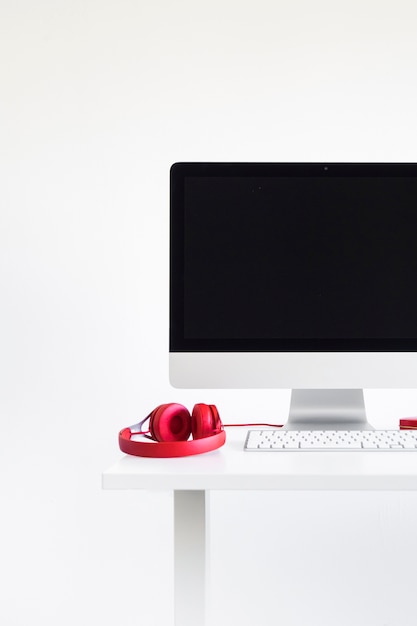 Keyboard near monitor and red headphones on table