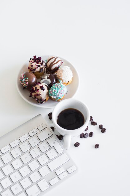 Keyboard near mug and biscuits on plate