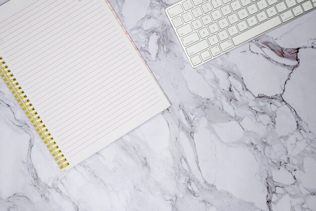 Keyboard and notebook on marble surface