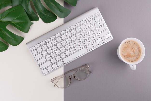 Keyboard with coffee cup and glasses on table