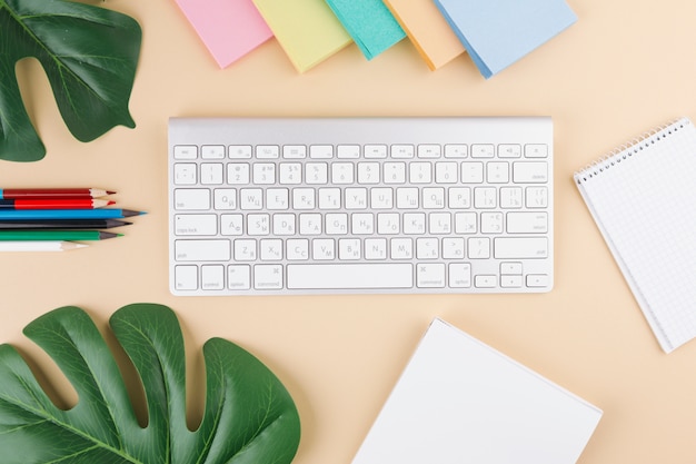 Free photo keyboard with notebooks and pencils on table