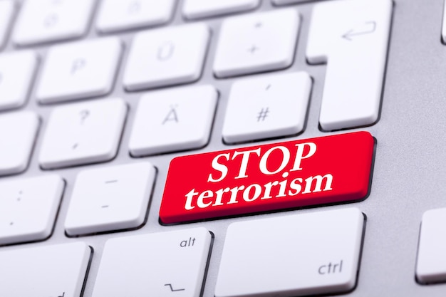 Клавиатура с красной кнопкой и словом "остановить терроризм" на ней. Остановить войну и насилие