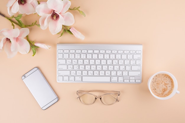 Keyboard with smartphone and flowers on table