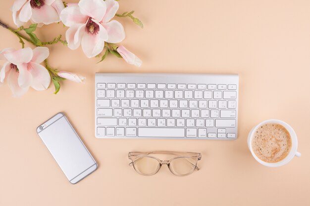 Keyboard with smartphone and flowers on table