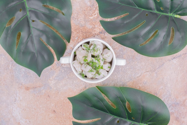 Foto gratuita pasta khinkali con ripieni ed erbe tritate in una ciotola bianca.