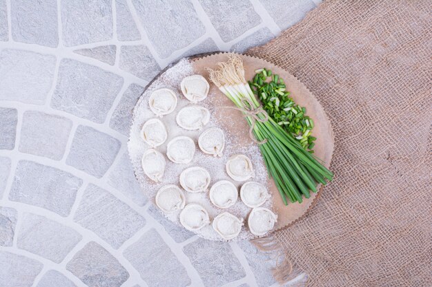 Khinkali stuffings in flour served with a bunch of green onion.