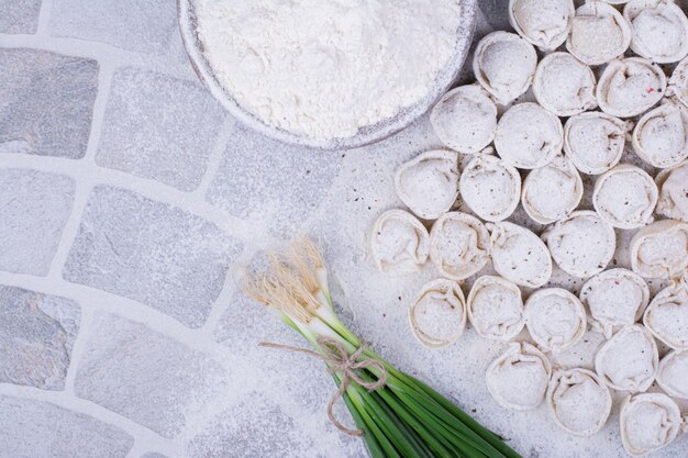 Khinkali stuffings in flour served with a bunch of green onion.