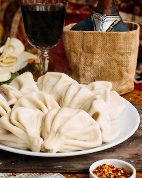 Foto gratuita khinkali con carne e bicchiere di vino rosso