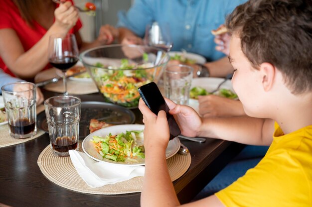 가족 저녁 식사를 하는 동안 스마트폰으로 검색하는 아이