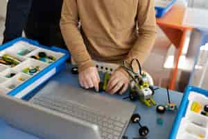 Foto gratuita ragazzo che costruisce un robot usando parti elettroniche