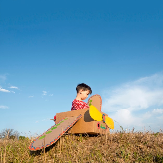 Kid in cardboard boat outdoors