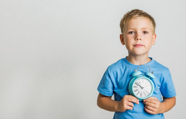 Kid in casual clothes holding a clock