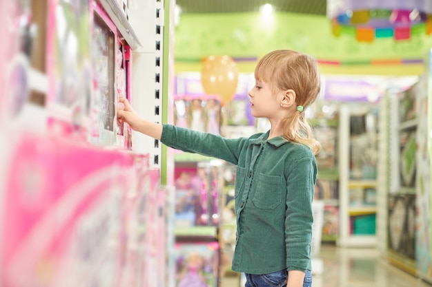 무료 사진 큰 가게에서 구입하기 위해 장난감을 선택하는 아이.