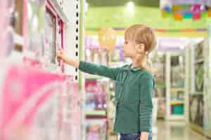 Free photo kid choosing toys for purchase in big store.