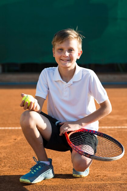 Kid crouching on the tennis field