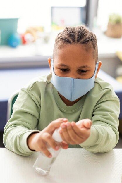 Kid disinfecting his hands in the classroom