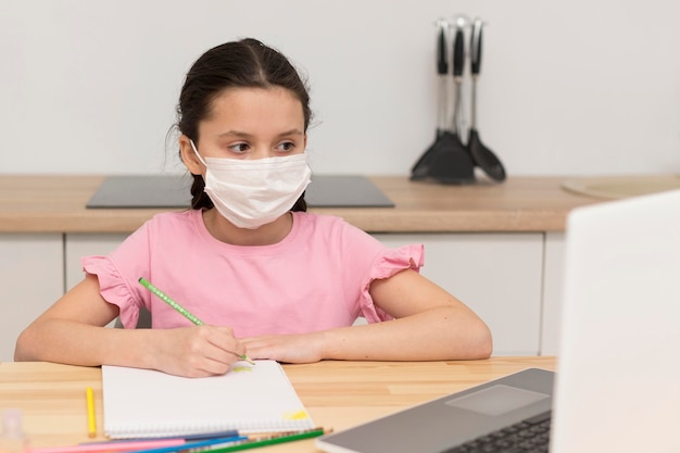 Free photo kid doing homework with mask