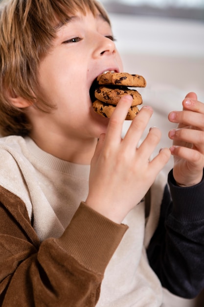 Free photo kid eating cookies at home