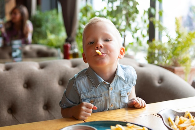 Kid eating french fries at restaurant