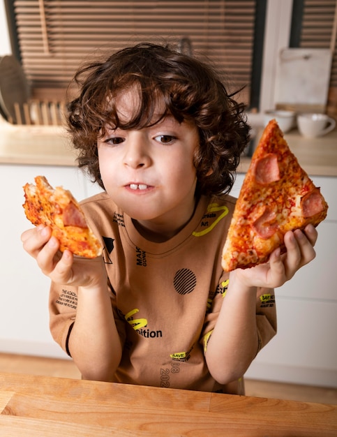 Free photo kid eating pizza at home