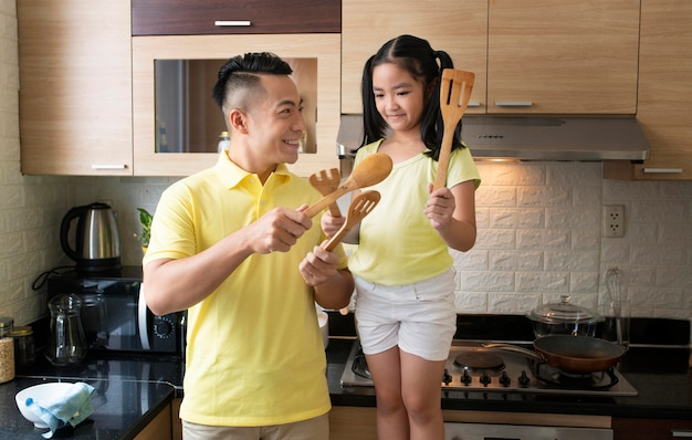 Kid and father holding kitchen tools