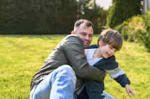 Free photo kid and father playing on grass