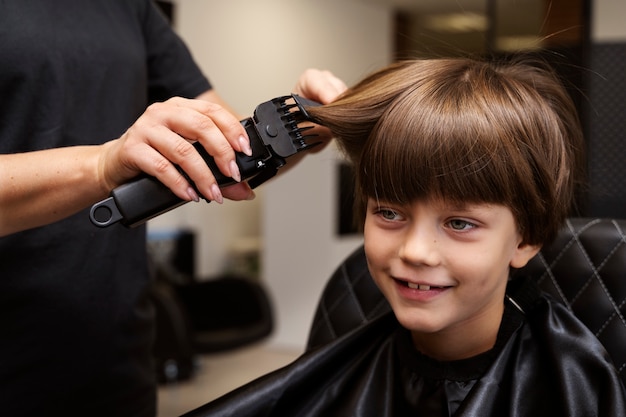 Free photo kid getting haircut  at salon side view