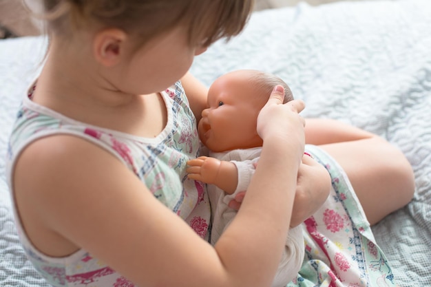Ragazza del bambino che gioca con la bambola nella cura dell'allattamento al seno