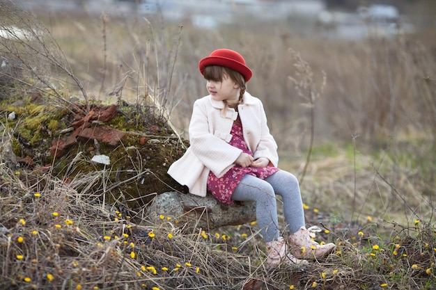 帽子をかぶったおさげの子供の女の子は、春の公園を散歩します