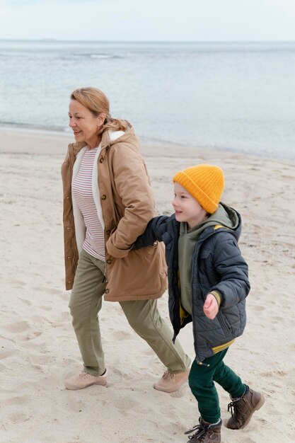 Kid and grandmother at beach full shot