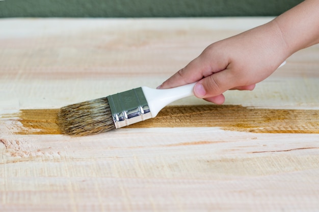 Free photo kid hand varnishing a wooden shelf using paintbrush