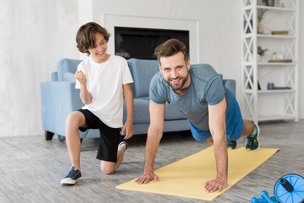 Малыш и его отец занимаются спортом дома
